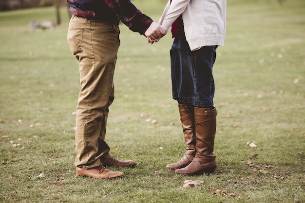 Beautiful shot of a couple holdings hands while standing on a grassy field with blurred background