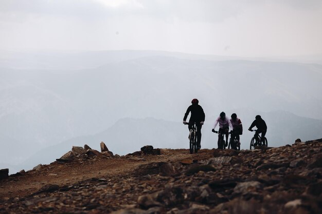 Beautiful shot of cyclers on a mountain with cloudy skies in the background