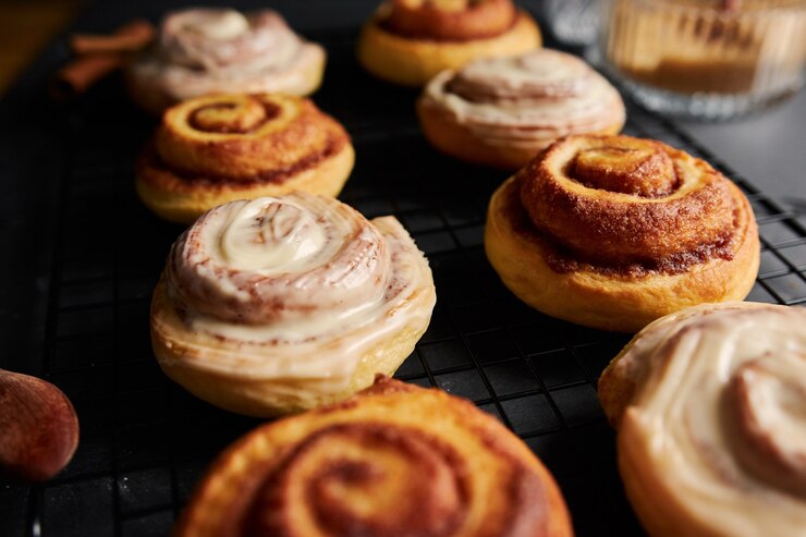 Free Photo beautiful shot of delicious cinnamon rolls with white glaze on a black table