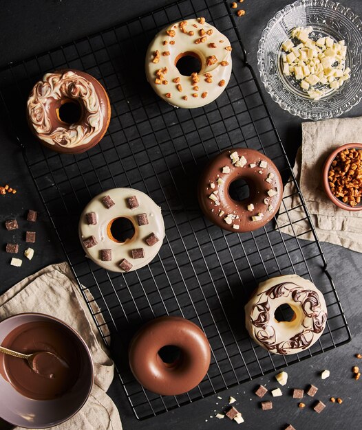 Foto gratuita bellissimo scatto di deliziose ciambelle ricoperte di glassa con gli ingredienti su un tavolo