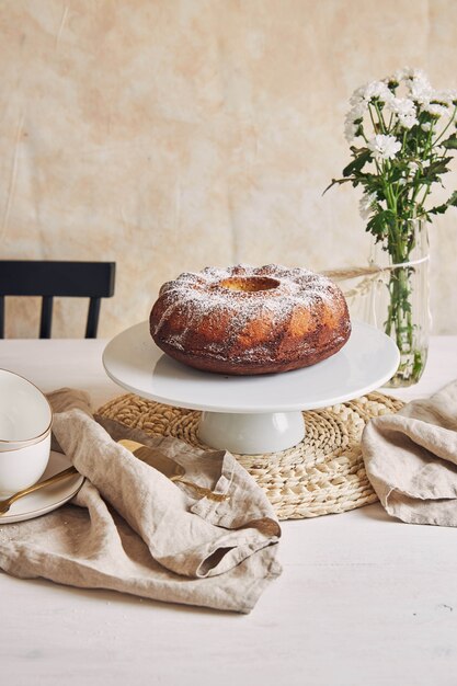 Beautiful shot of a delicious ring cake put on a white plate and a white flower near it