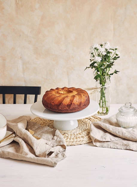 Beautiful shot of a delicious ring cake put on a white plate and a white flower near it