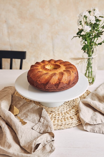 Beautiful shot of a delicious ring cake put on a white plate and a white flower near it