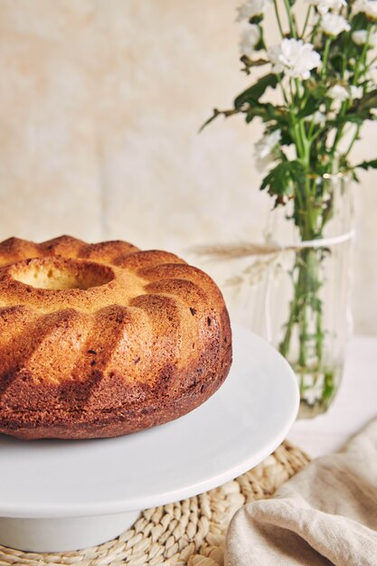 Beautiful shot of a delicious ring cake put on a white plate and a white flower near it