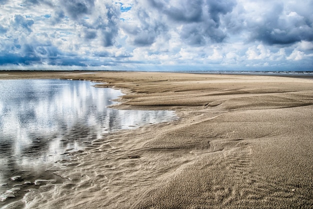 Free photo beautiful shot of the deserted sandy shore of the ocean under the cloudy sky