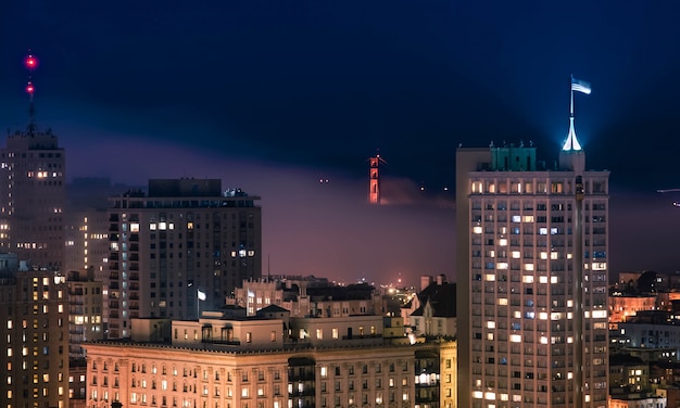 Beautiful shot of the downtown San Fransisco building with the golden gate bridge at night time
