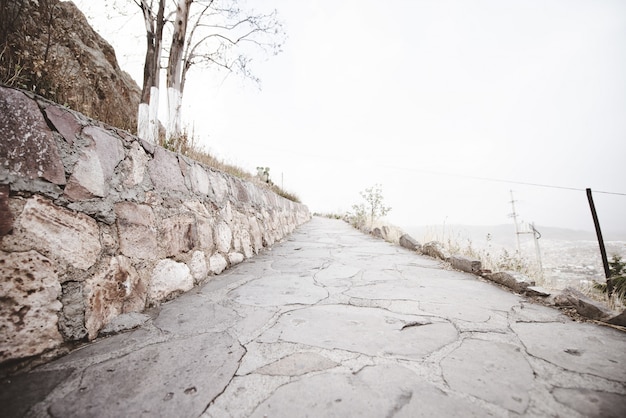 Beautiful shot of an empty pathway on the side of a mountain with a cloudy sky