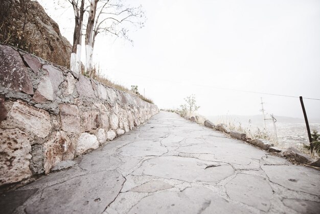 Beautiful shot of an empty pathway on the side of a mountain with a cloudy sky