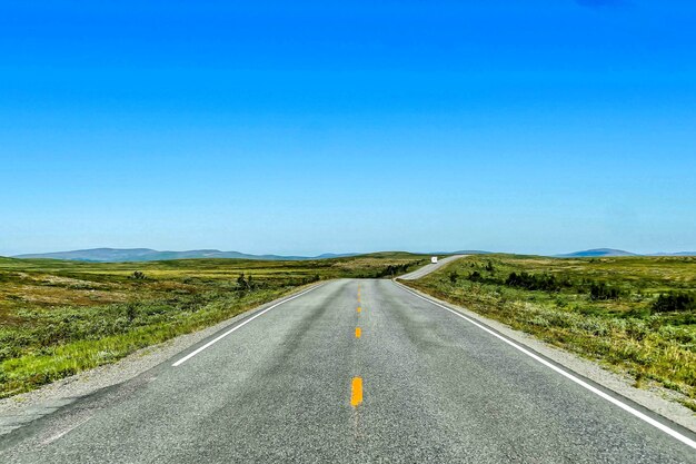 Красивый снимок пустой дороги под голубым небом в дневное время