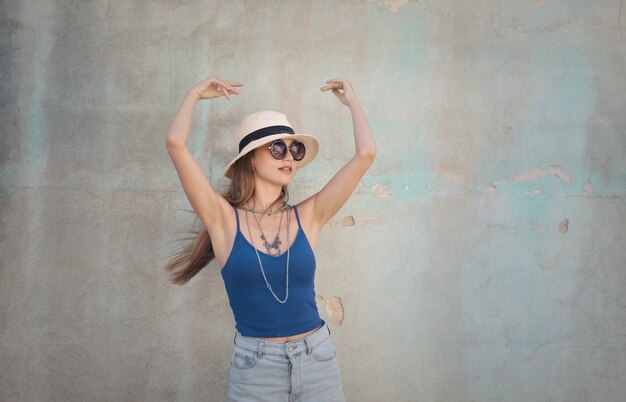 Beautiful shot of a female in blue sleeveless wearing sunhat and glasses and other accessories