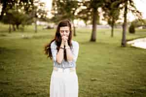 Free photo beautiful shot of a female with her hands near her mouth while praying with a blurred background