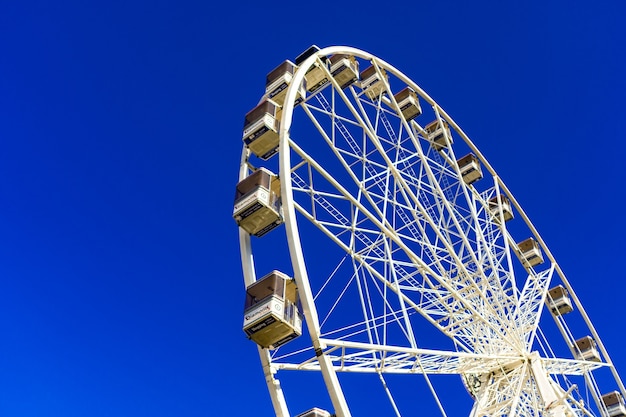 Красивый снимок колеса обозрения в парке развлечений на фоне голубого неба