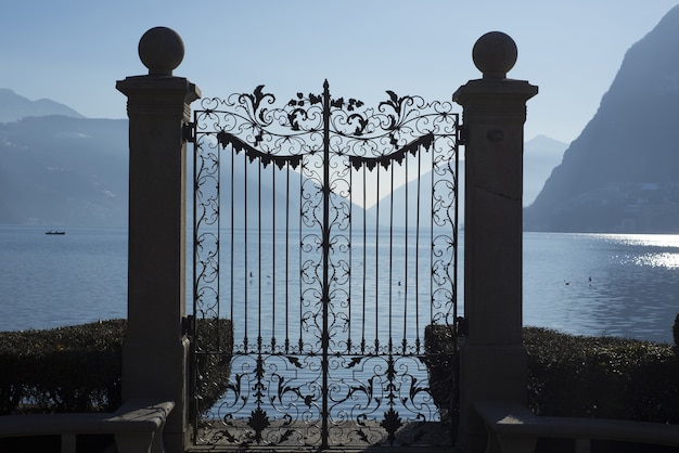 Foto gratuita bella ripresa di un cancello sul lago alpino di lugano con montagne in ticino, svizzera