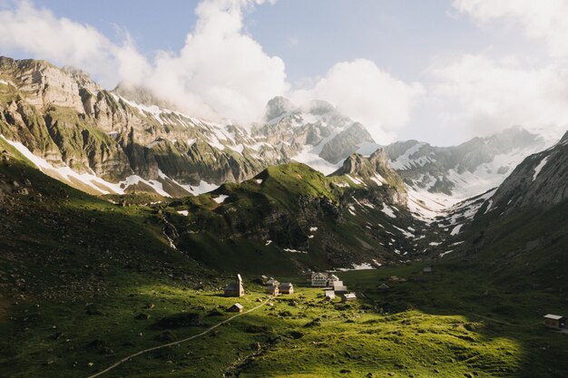 Beautiful shot of green mountains covered with snow under a sky with white clouds