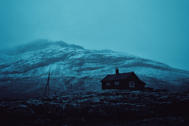Foto gratuita bellissimo scatto di una casa su una collina con una montagna incredibile