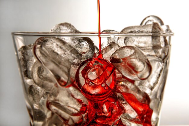 中に赤い液体が注がれているガラスの角氷の美しいショット