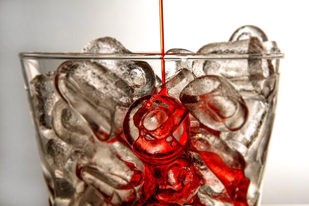 Beautiful shot of ice cubes in a glass with a red liquid pouring inside