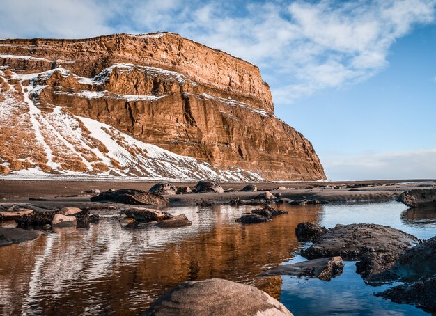 Beautiful shot of a lake in front of a snowy mountain with blue sky