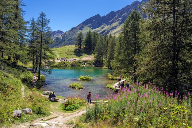 Foto gratuita bella ripresa di un lago vicino alle montagne e circondato da alberi e persone