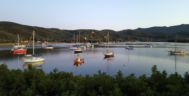 Beautiful shot of a lake with boats surrounded by mountains and trees