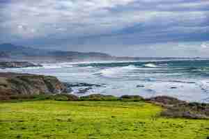 Free photo beautiful shot of a lighthouse on a green rock formation at the ocean shore