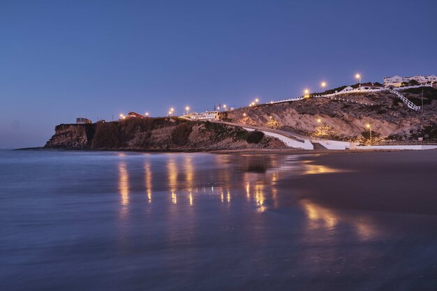 Beautiful shot of lights on a rocky hill in the beach with a clear blue sky