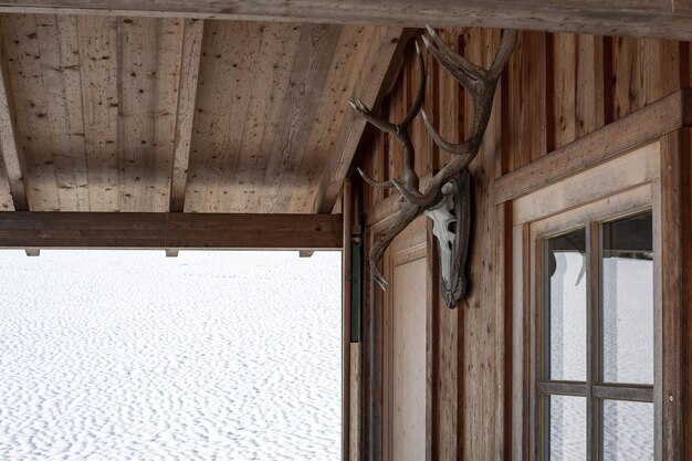 鹿の角が窓の横にぶら下がっていて、後ろに雪が降っているロッジハウスの美しいショット