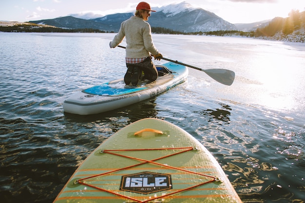 Beautiful shot of a male sitting on a paddleboard holding an oar with mountains 