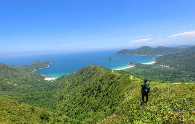 Beautiful shot of a man standing on a landscape of forested hills and a blue ocean