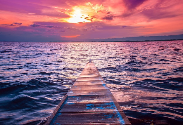 Free photo beautiful shot of the nose of a small boat sailing in the sea with amazingclouds in the red sky