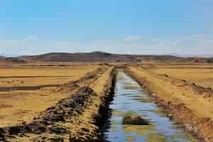 無料写真 丘を背景にした砂漠のような地域の真ん中にある灌漑用水路の美しいショット