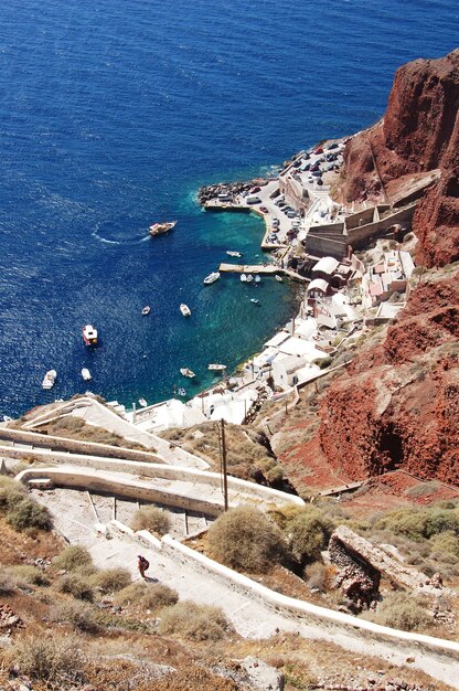 Beautiful shot of the old buildings near the cliff in the shore with boats in the ocean