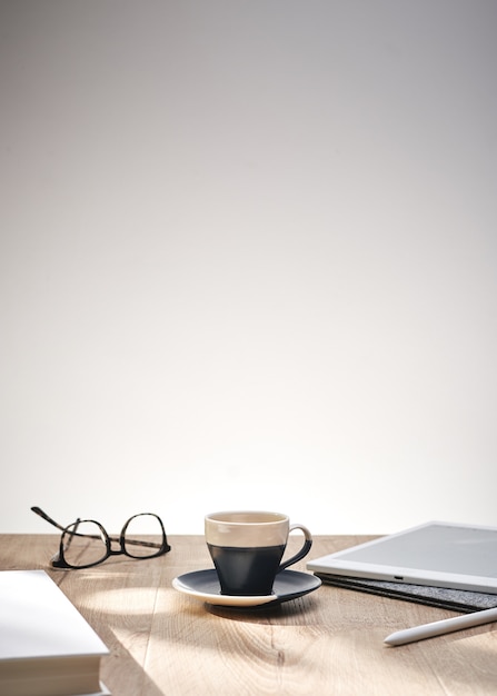 Beautiful shot of optical glasses and a cup on a table with a white background and space for text