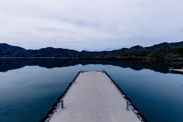 Beautiful shot of a pathway on the water with mountains in the distance under a cloudy sky