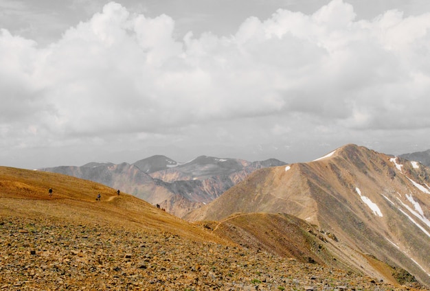 Beautiful shot of people walking up the mountain in the distance under a cloudy sky