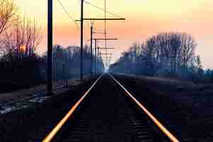 Free photo beautiful shot of a railroad in the countryside with the amazing pink sky at dawn