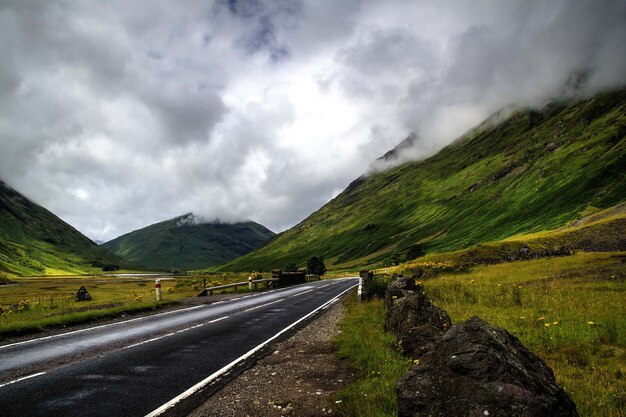 曇り空の下で山々に囲まれた道路の美しいショット