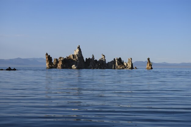 澄んだ空の下、海の真ん中にある岩の美しいショット