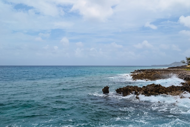 Beautiful shot of rocks on a seashore with a cloudy blue sky