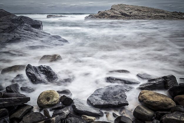 Beautiful shot of rocks in the seashore with a gloomy sky