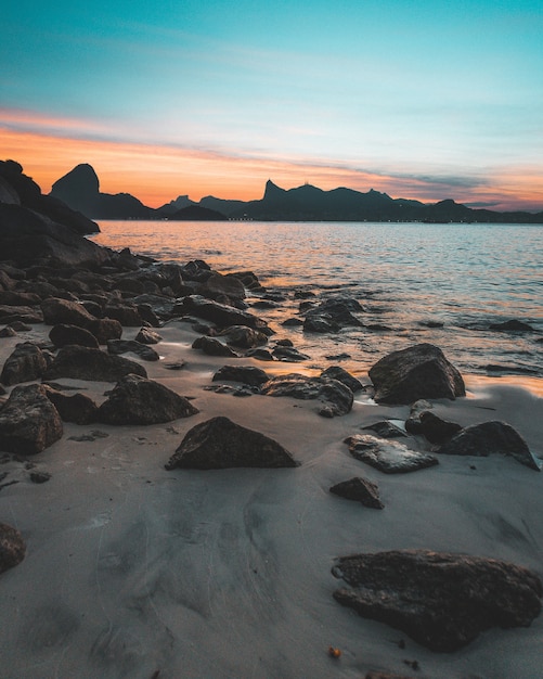 Beautiful shot of the rocky coast of the sea at sunset with amazing blue sky