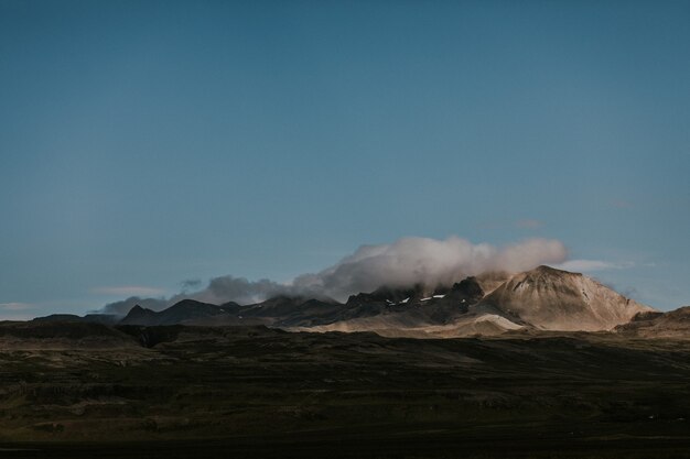 Beautiful shot of rocky hills covered with white clouds in a green land