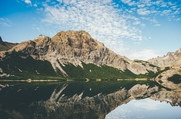 Красивая съемка скалистой горы рядом с озером с отражением в воде