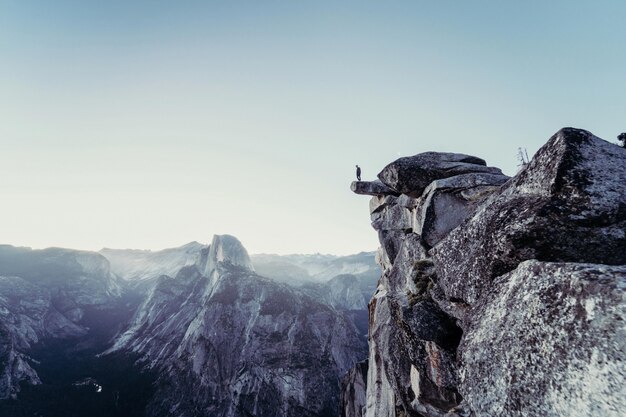 Beautiful shot of rocky mountains with a person standing on the edge