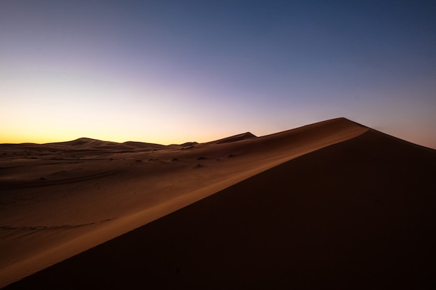 Beautiful shot of sand dunes under a purple and blue sky