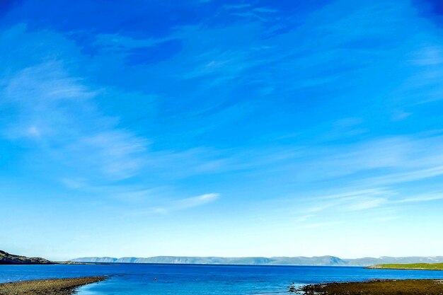 Beautiful shot of a sea with mountains in the distance under a blue sky