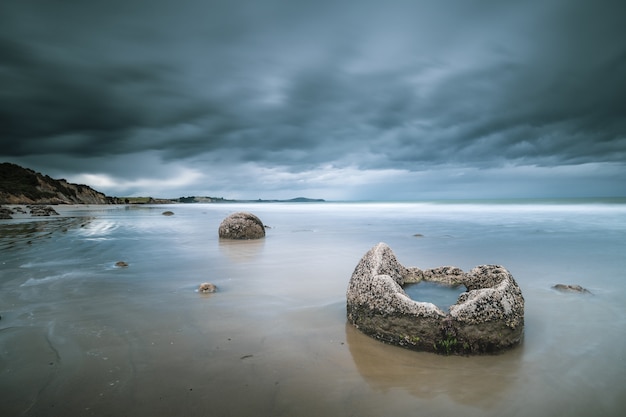 Beautiful shot of the sea with rocks and mountains in the distance under a blue cloudy sky