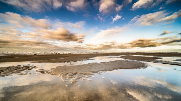 Beautiful shot of the seashore with water ponds under a blue sky