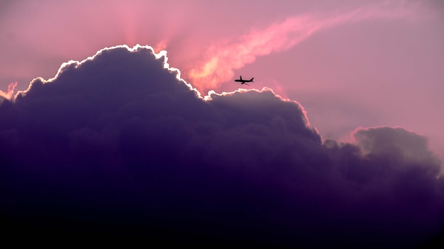 Beautiful shot of the silhouette of the plane flying in the sky during sunrise