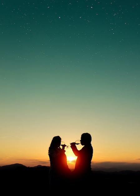 夕暮れ時にワインを飲むカップルのシルエットの美しいショット